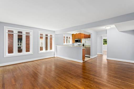 an empty living room with a kitchen in the background
